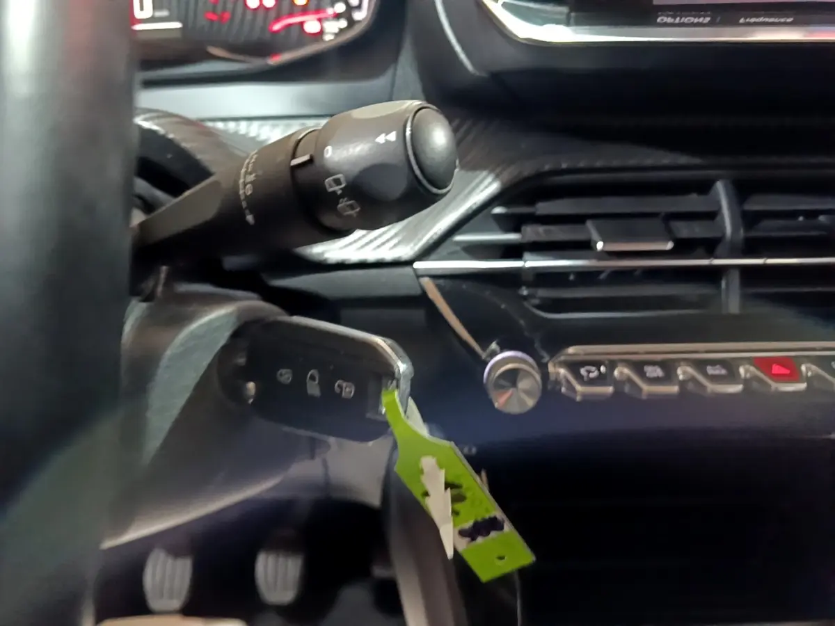 Gros plan intérieur sur la colonne de direction et tableau de bord noir de la Peugeot 208 2020, version BlueHDi Active Business.