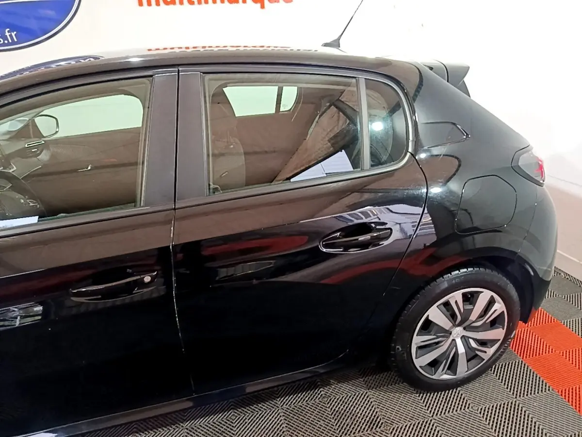Vue de profil côté droit d'une Peugeot 208 noire, mettant en valeur les jantes et la ligne arrière du véhicule.