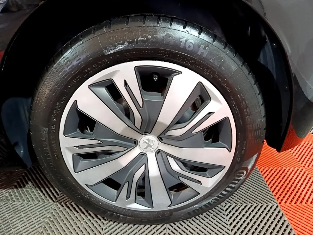 Gros plan sur la roue avant droite noire d'une Peugeot 208 2020 avec jante en alliage au design moderne.