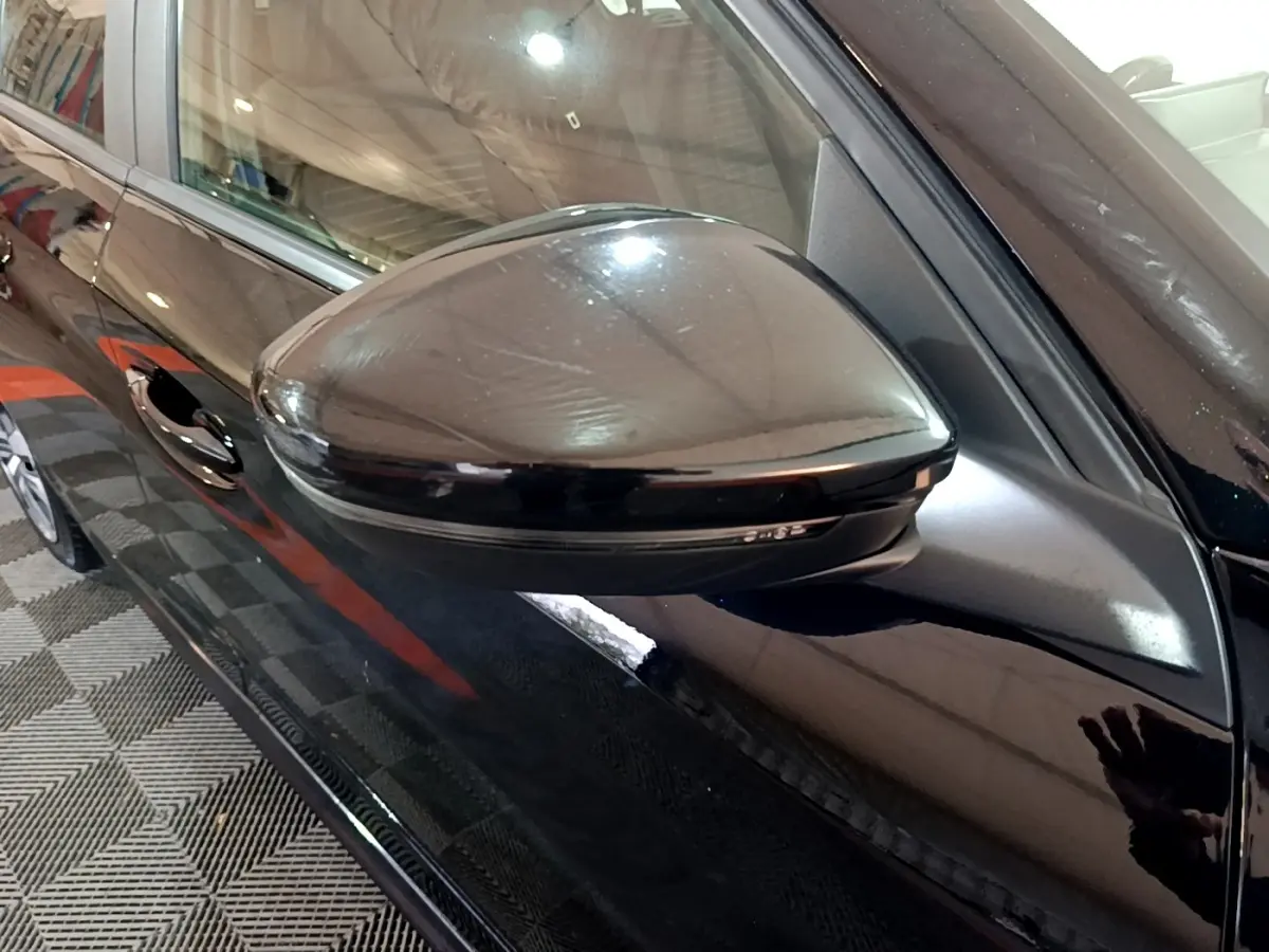 Vue rapprochée du rétroviseur droit noir brillant d'une Peugeot 208 2020, avec portière et poignée visibles.