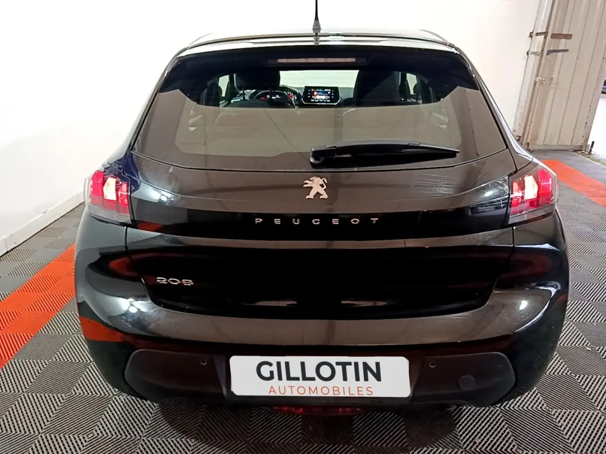 Vue arrière d'une Peugeot 208 noire de 2020 avec feux arrière allumés et logo lion centré sur le hayon.