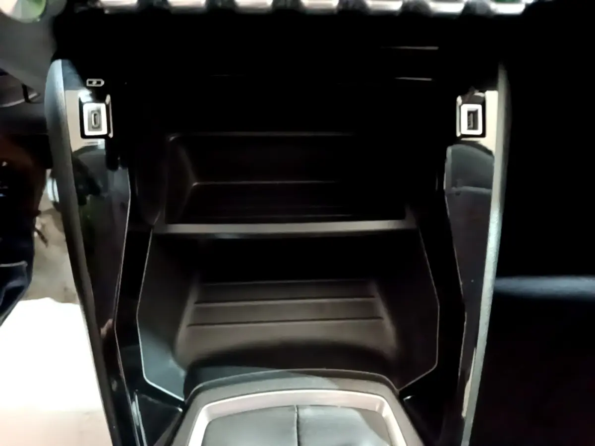 Gros plan sur la console centrale noire de la Peugeot 208 2020, avec ports USB visibles de chaque côté.