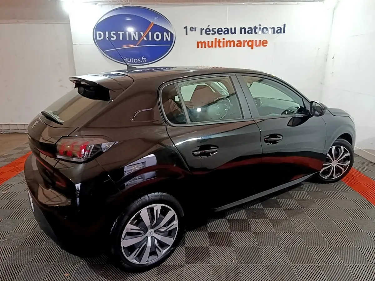 Peugeot 208 BlueHDi 100 S&S Active Business noir vue 3/4 arrière droit en intérieur sur sol damier.
