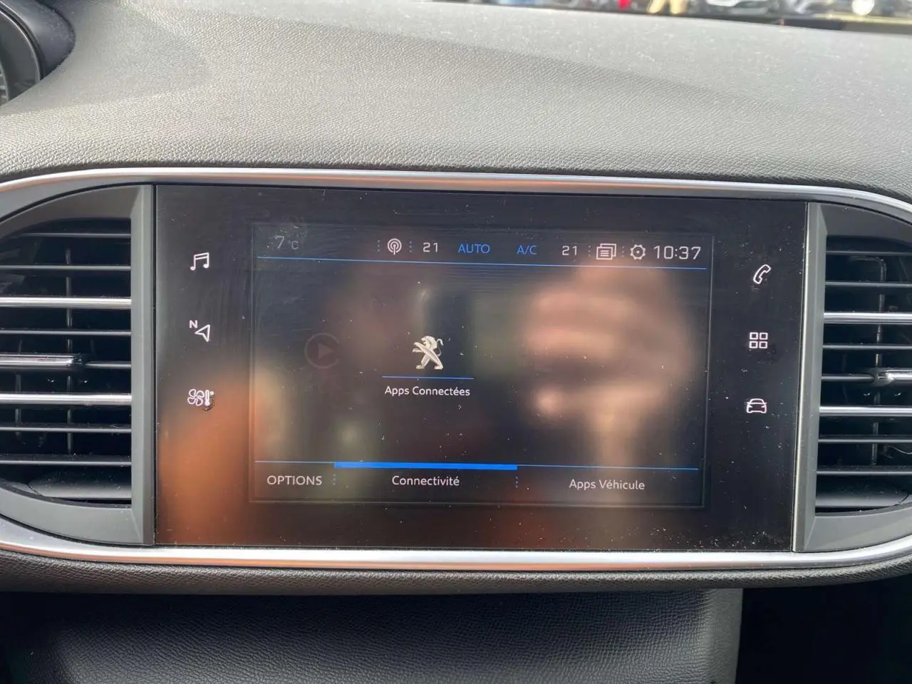 Vue rapprochée de l’écran tactile central du tableau de bord d’une Peugeot 308 bleu foncé, affichant les apps connectées.