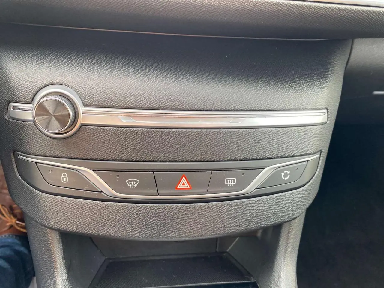 Gros plan sur la console centrale noire de la Peugeot 308 2018, avec boutons de verrouillage et feux de détresse rouges.