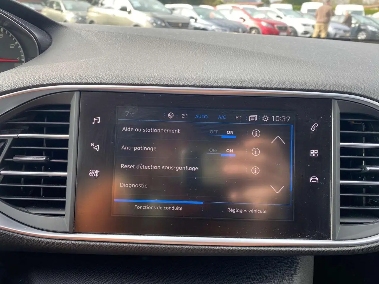 Écran tactile central de la Peugeot 308 2018 affichant les aides à la conduite, entouré de grilles d’aération noires.