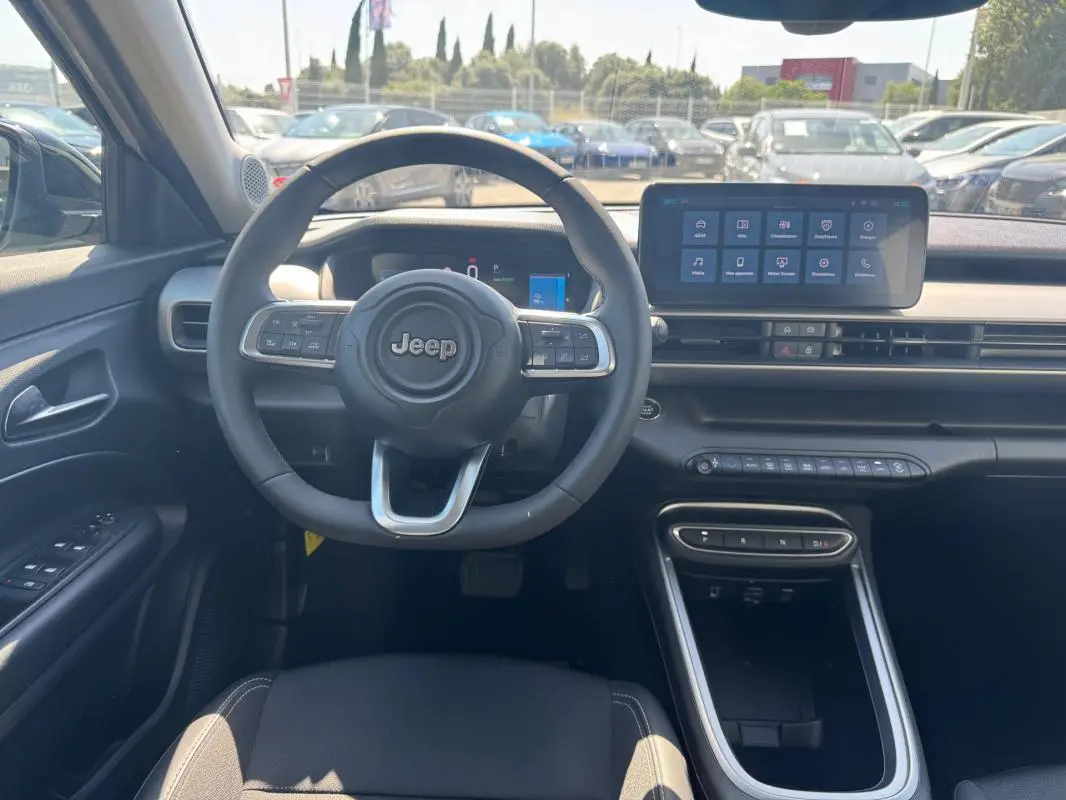 Vue intérieure frontale du tableau de bord et volant cuir du Jeep Avenger électrique blanc 2025 avec écran tactile central.