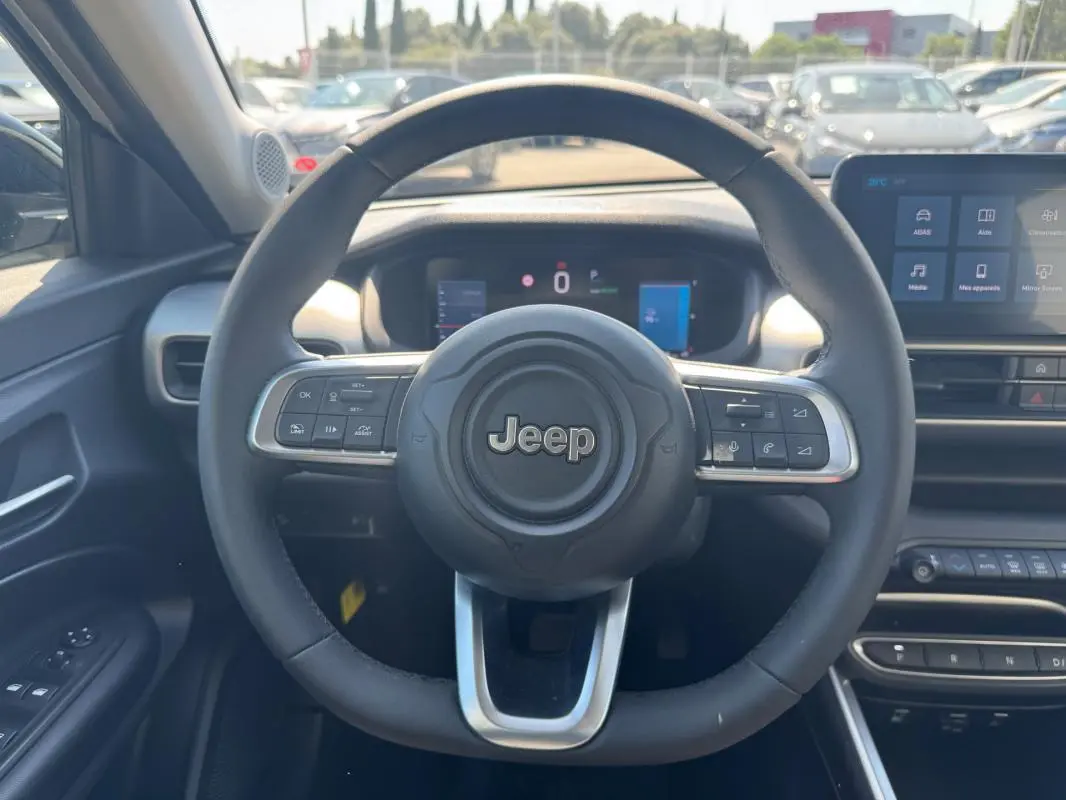 Vue intérieure centrée sur le volant cuir du Jeep Avenger électrique 2025 avec tableau de bord numérique et écran tactile.
