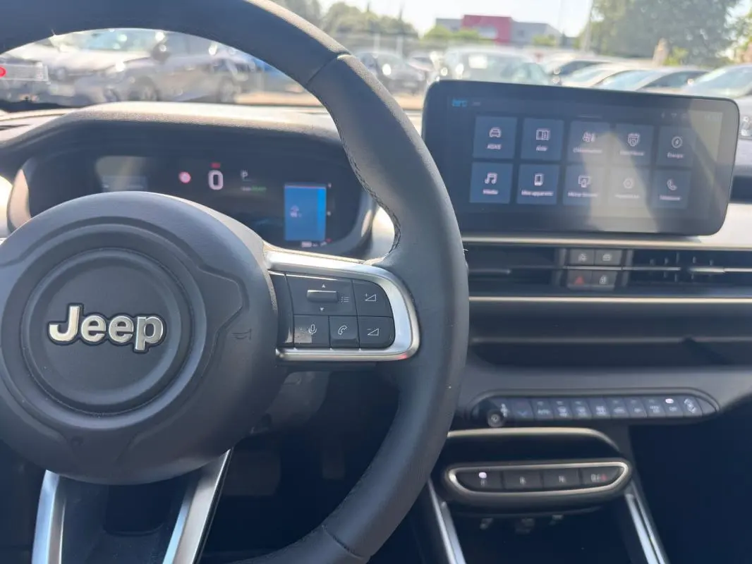 Vue intérieure centrée sur le volant cuir Jeep et l’écran tactile du tableau de bord du Jeep Avenger électrique.