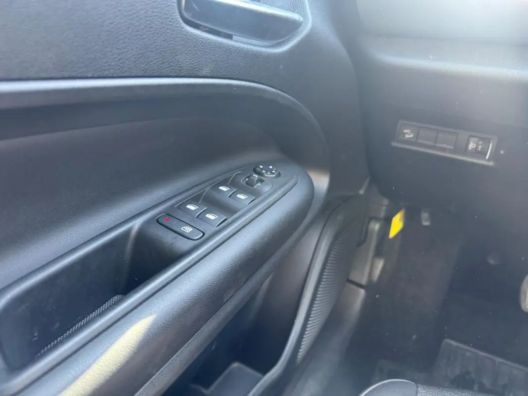 Gros plan sur le panneau de commandes des vitres électriques côté conducteur du Jeep Avenger 2025, intérieur noir.