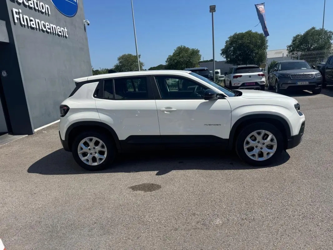 Profil latéral droit d'un Jeep Avenger électrique blanc 2025 avec jantes alliage 17 pouces et toit ouvrant en verre.