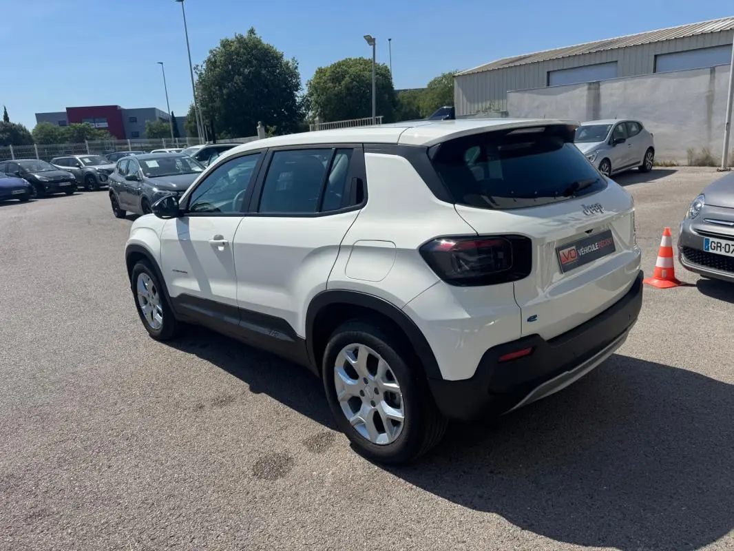 Jeep Avenger électrique blanc vu en 3/4 arrière droit, avec jantes alliage 17 pouces et toit noir contrasté.