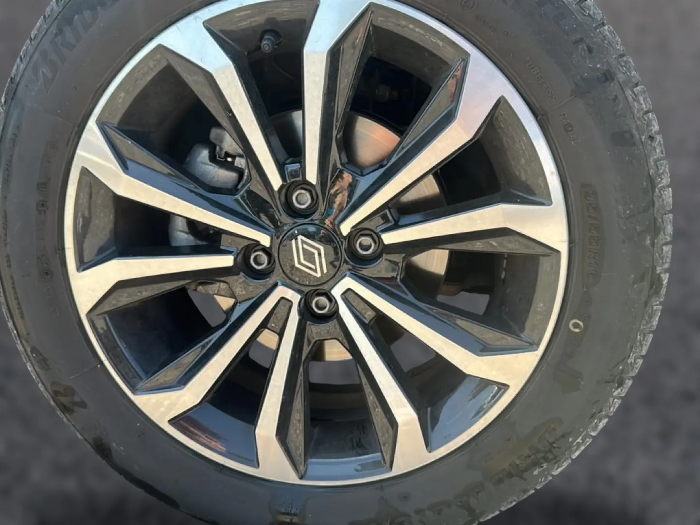 Gros plan sur une jante alliage bicolore noire et argent avec logo Renault central, montée sur pneu Bridgestone.