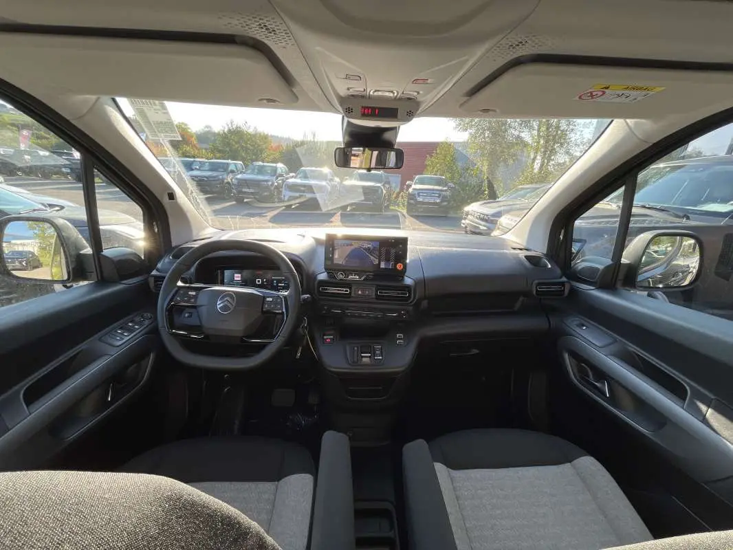 Vue intérieure avant du Citroën Berlingo 2026, tableau de bord noir avec écran tactile et sièges tissu gris et noir.