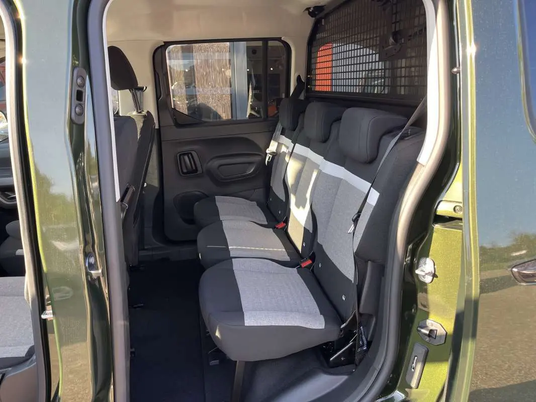 Vue latérale intérieure du Citroën Berlingo Sirkka green montrant les trois sièges arrière indépendants et la grille de séparation.