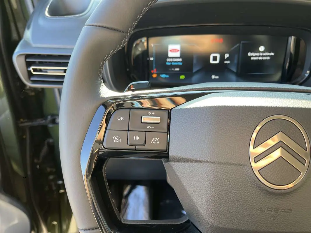 Gros plan sur le volant cuir gris du Citroën Berlingo Sirkka green 2026 avec commandes multifonctions et tableau de bord numérique.