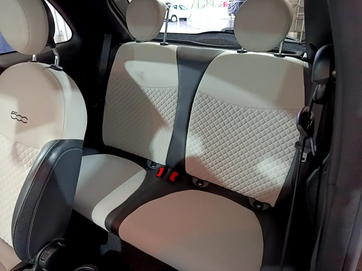 Vue intérieure montrant la banquette arrière beige et noire avec surpiqûres, et l'avant du siège conducteur de la FIAT 500.