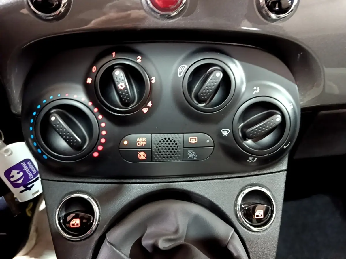 Vue rapprochée des commandes de climatisation et du levier de vitesses d'une Fiat 500 gris foncé, version 2022.
