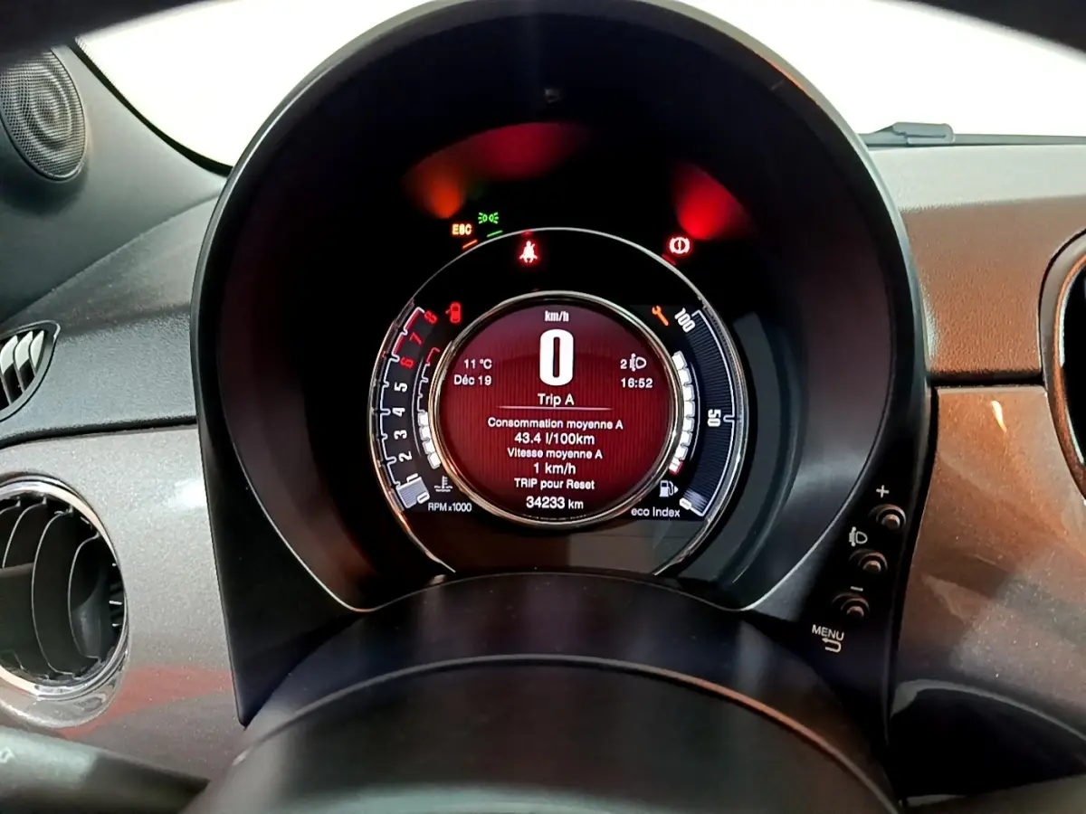 Vue rapprochée du tableau de bord numérique circulaire de la Fiat 500 gris foncé, affichant les informations de conduite.