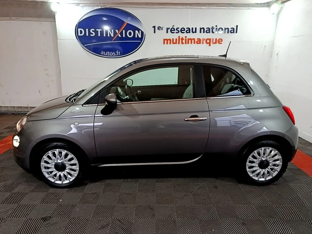 Profil droit d'une Fiat 500 gris foncé 2022, version Dolcevita, avec jantes alliage et intérieur visible.
