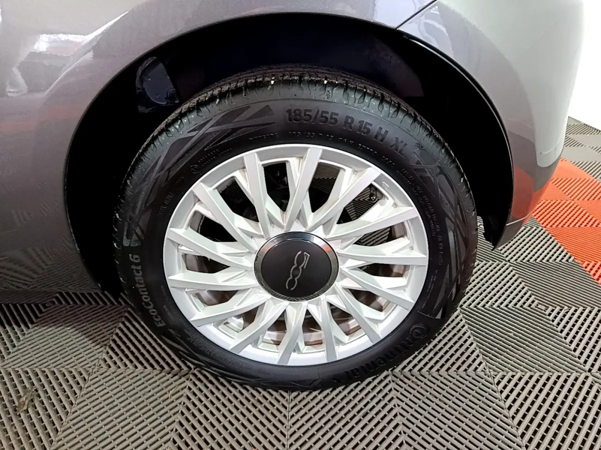 Gros plan sur la roue avant gauche gris foncé de la Fiat 500 avec jante argentée à rayons fins.