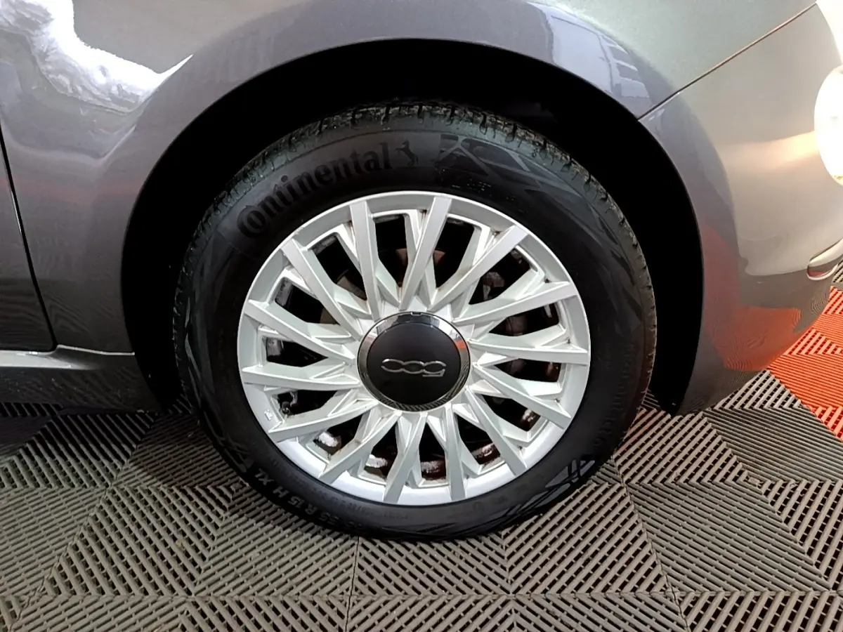 Gros plan sur la roue avant droite gris foncé d'une FIAT 500 1.0 70ch BSG Dolcevita avec jante argentée à rayons fins.