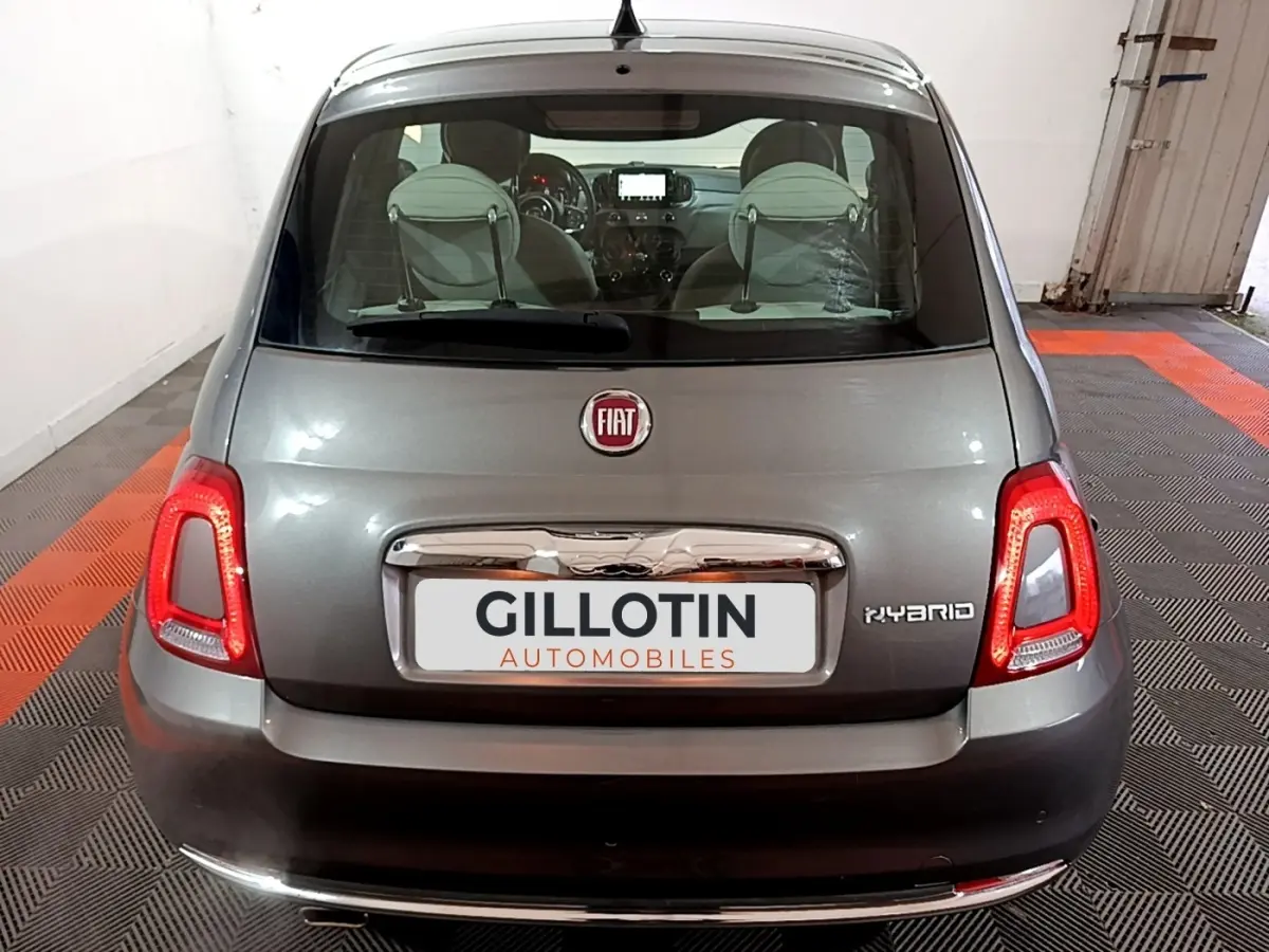 Vue arrière d'une FIAT 500 gris foncé hybride, avec feux LED allumés et logo FIAT visible sur le coffre.