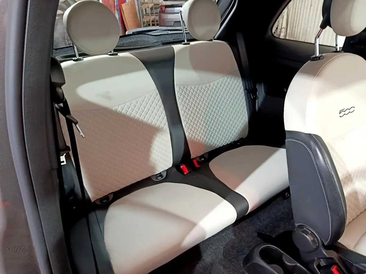 Vue intérieure de la banquette arrière beige et noire du FIAT 500 1.0 70ch BSG Dolcevita, avec siège avant partiellement visible.