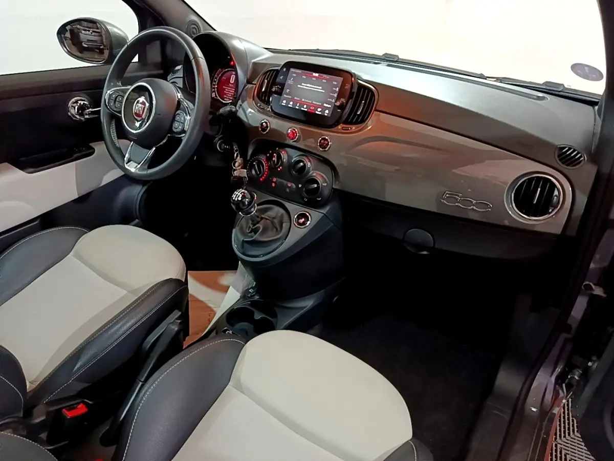 Vue intérieure côté conducteur de la Fiat 500 1.0 gris foncé avec tableau de bord brillant et volant cuir multifonctions.