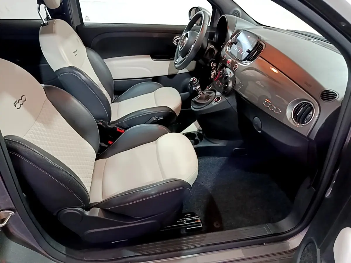 Vue intérieure côté conducteur de la Fiat 500 gris foncé, sièges bi-ton beige et noir avec logo 500 brodé.