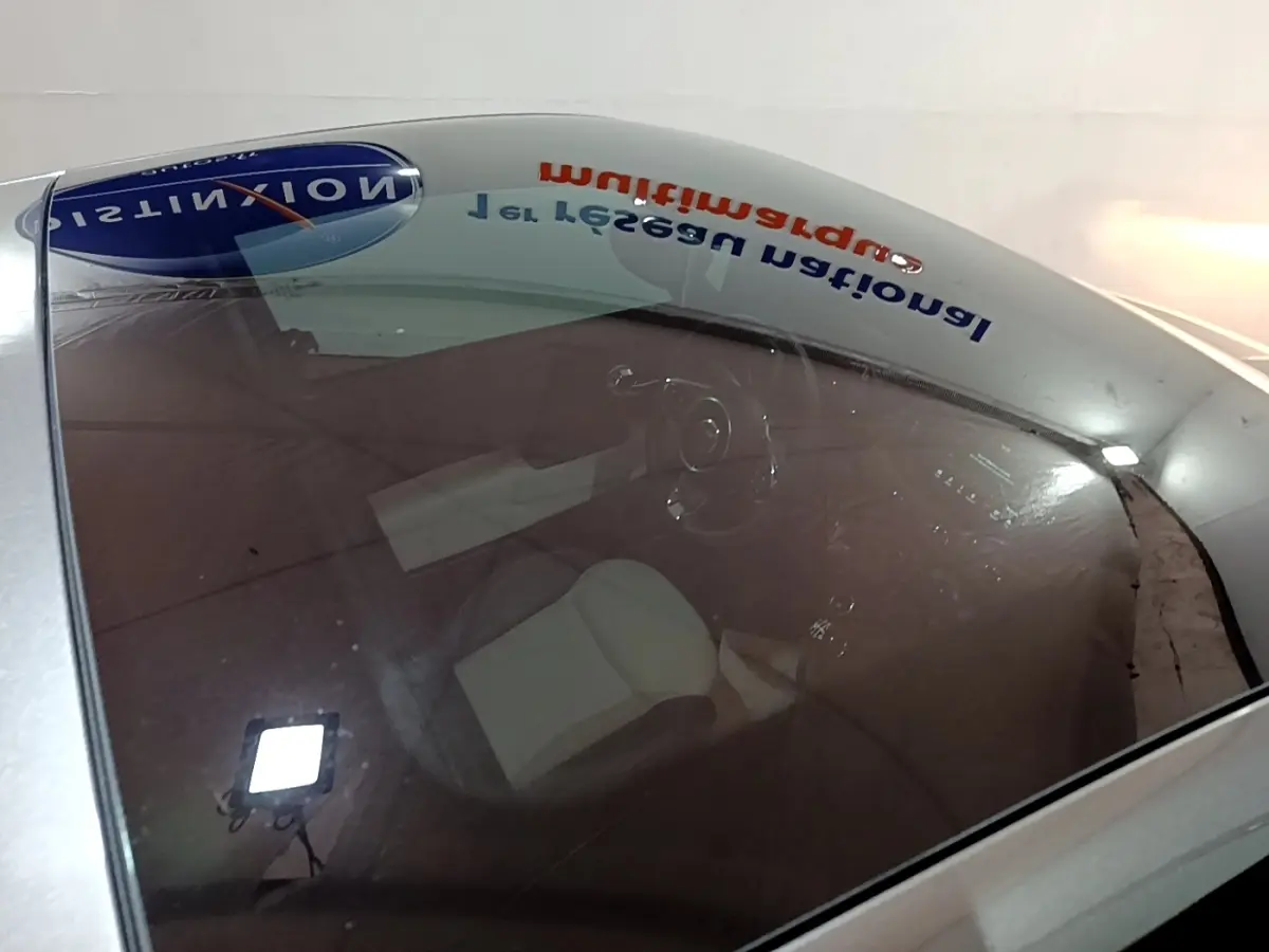 Vue plongeante sur l'intérieur d'une FIAT 500 gris foncé, volant cuir et sièges clairs visibles à travers le pare-brise.