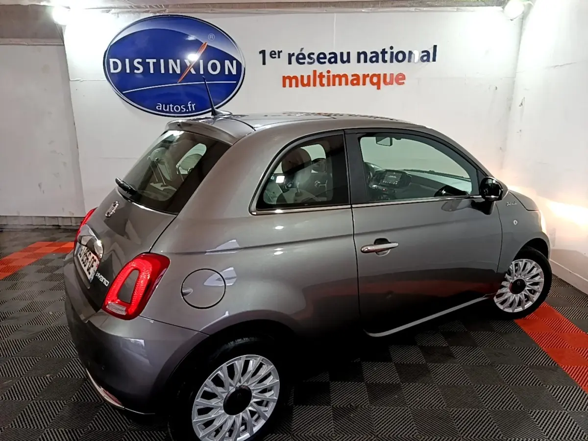 Vue 3/4 arrière droite d'une FIAT 500 gris foncé, avec jantes multibranches et feux arrière LED visibles.