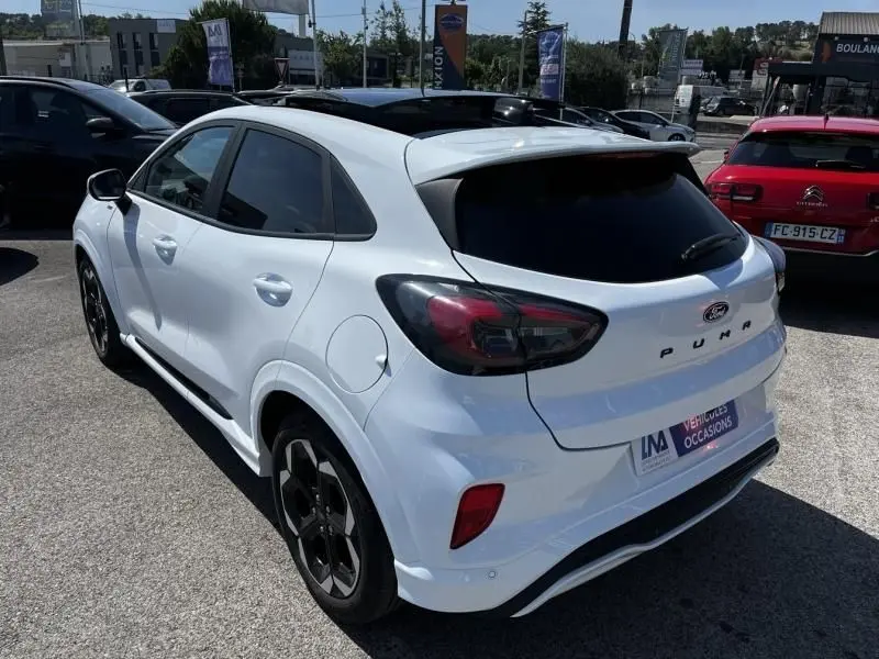 Vue 3/4 arrière droite d'un Ford Puma blanc 2025 ST-Line X avec feux arrière foncés et jantes noires distinctives.