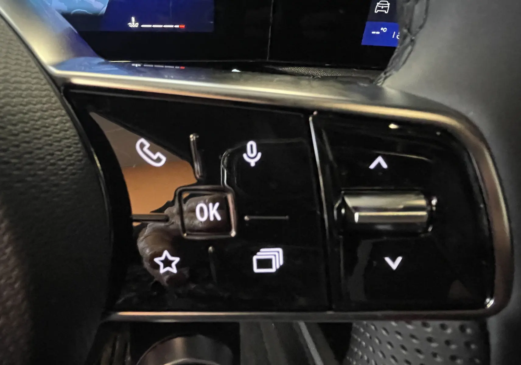 Gros plan sur les commandes multifonctions au volant côté gauche de la Renault Clio VI TCe 115ch Techno, intérieur noir.
