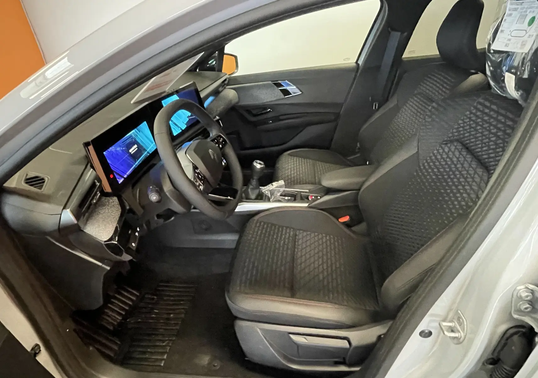 Vue intérieure côté conducteur de la Renault Clio VI TCE 115ch Techno gris Rafale, sièges noirs et tableau de bord digital.