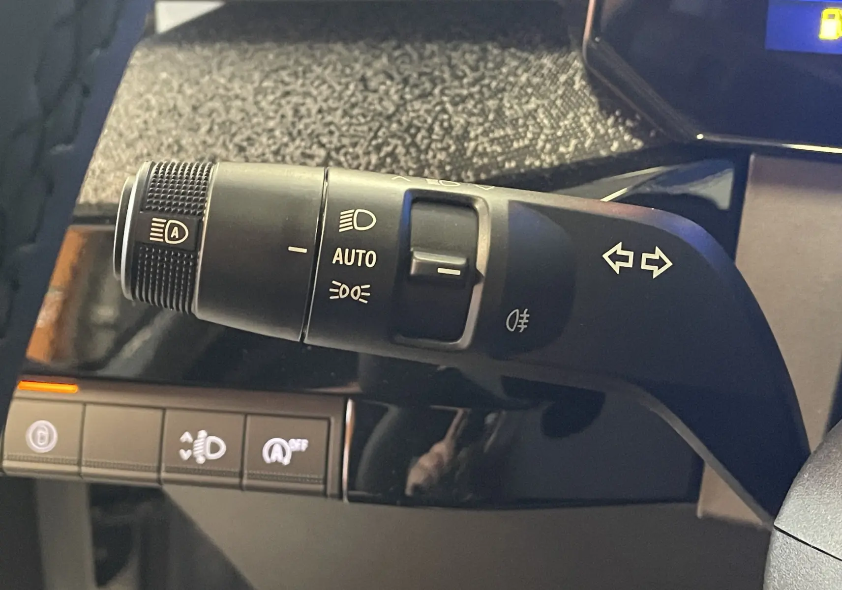 Gros plan sur la commande des feux et clignotants dans l’habitacle noir de la Renault Clio VI TCe 115ch Techno.