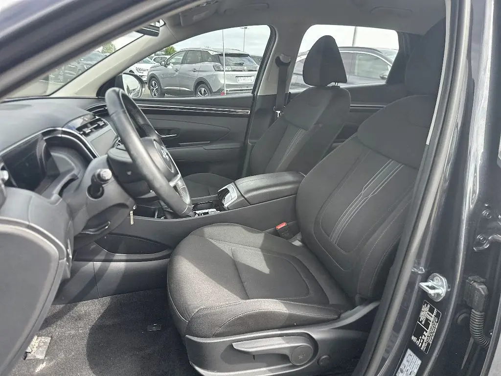 Vue intérieure côté conducteur du Hyundai Tucson gris 2023, montrant les sièges avant et le tableau de bord.