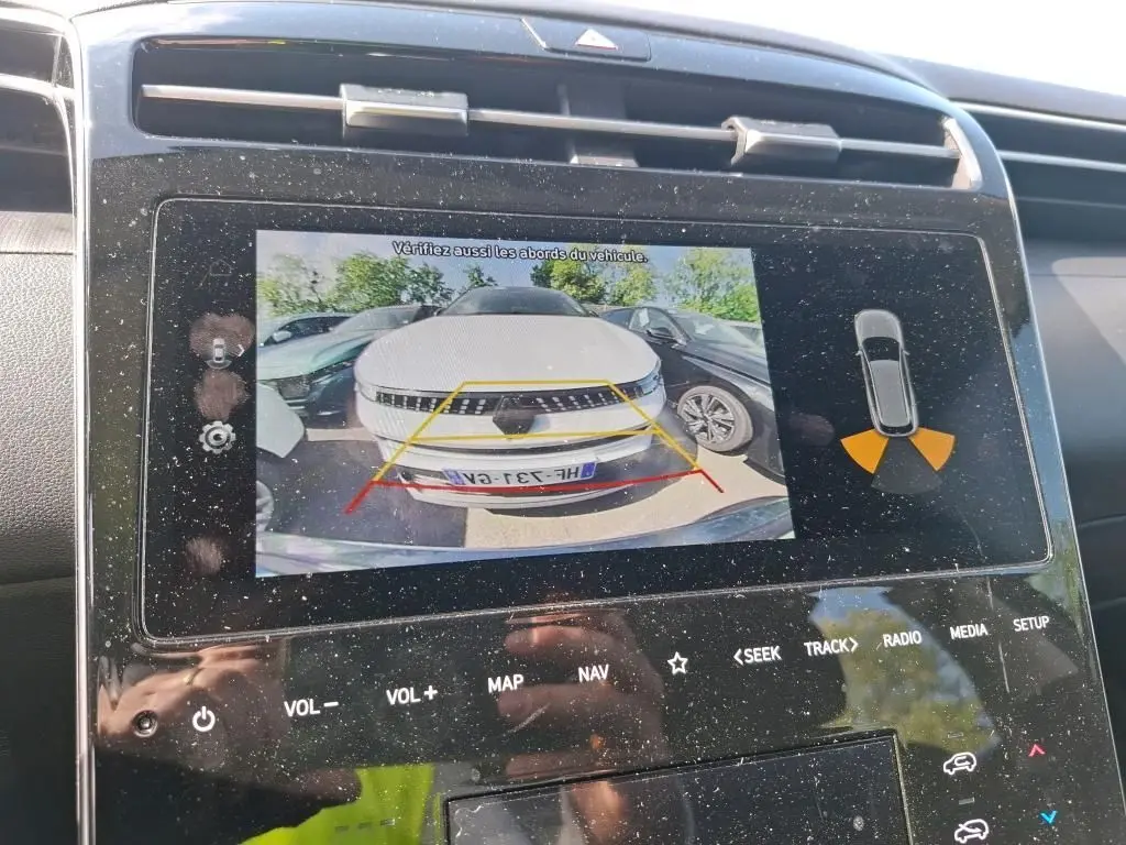 Affichage de la caméra de recul montrant un Hyundai Tucson gris de face, avec guidage de trajectoire sur l'écran intérieur.