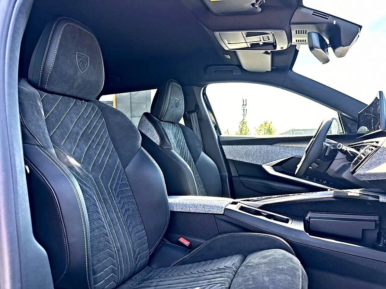 Intérieur avant du Peugeot 5008 Hybrid 145 GT 2025, sièges noirs en cuir et alcantara avec surpiqûres blanches.
