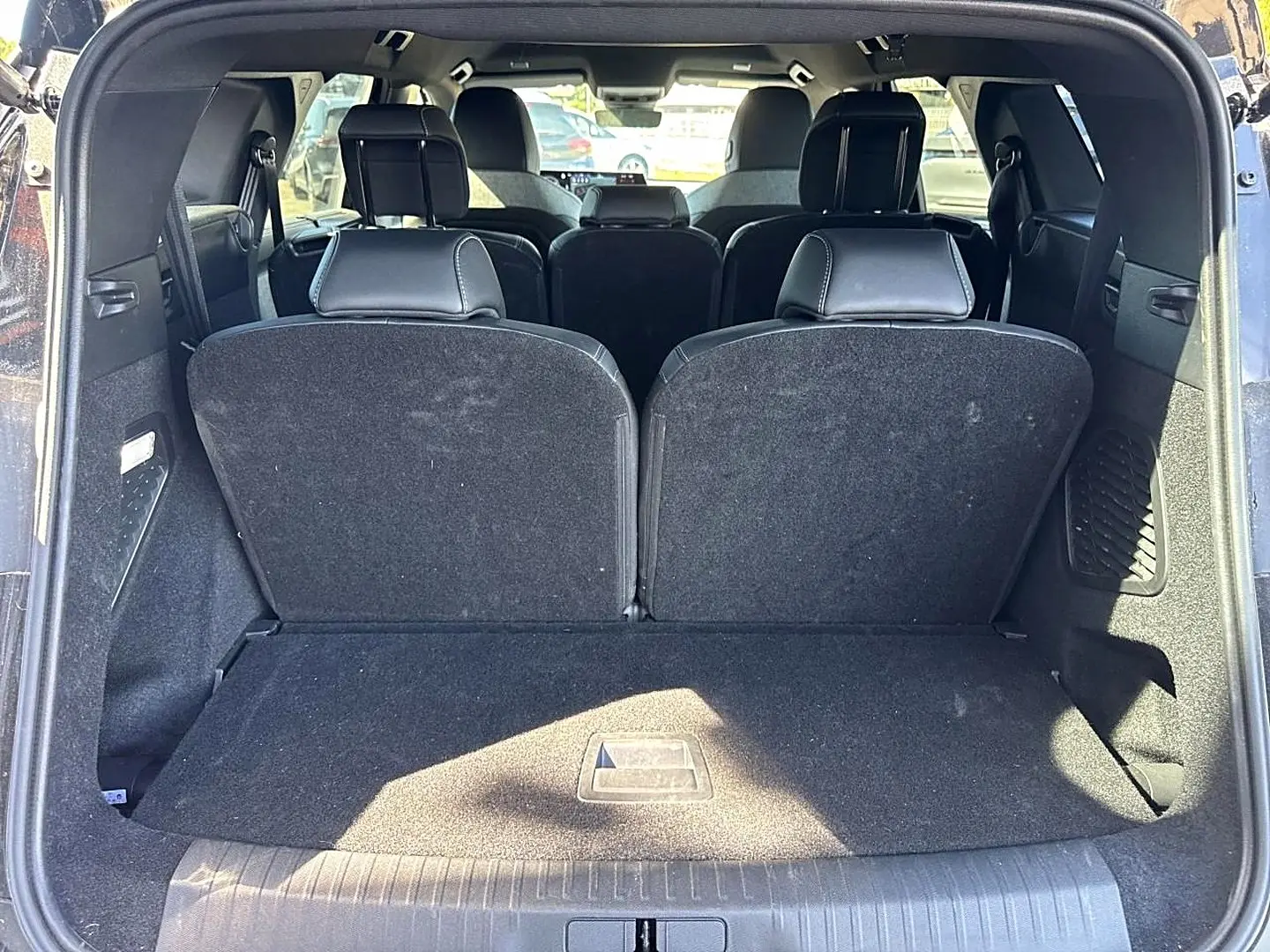 Vue arrière du coffre ouvert du Peugeot 5008 noir, montrant les sièges rang 3 relevés et l'intérieur spacieux.