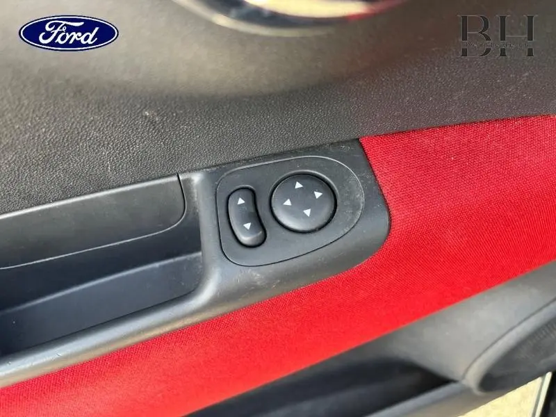 Détail des commandes de réglage des rétroviseurs sur la porte intérieure côté conducteur d'une FIAT 500 noire.