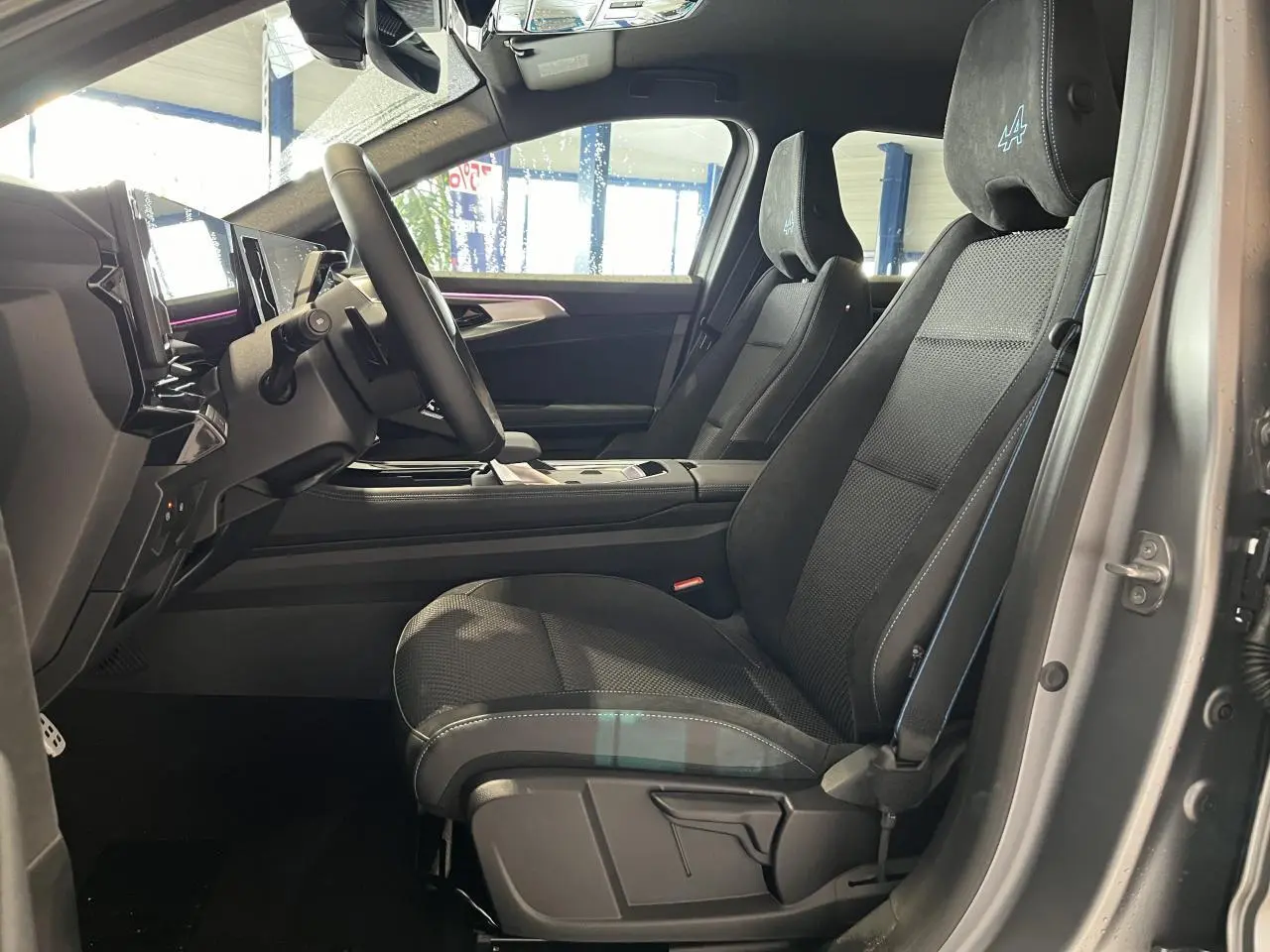 Vue intérieure côté conducteur du Renault Austral gris, mettant en valeur les sièges en tissu carbone Alcantara avec logo Alpine brodé.