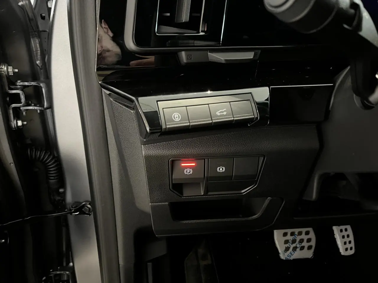 Gros plan sur les commandes noires côté gauche du tableau de bord d’un Renault Austral gris, avec pédalier aluminium.