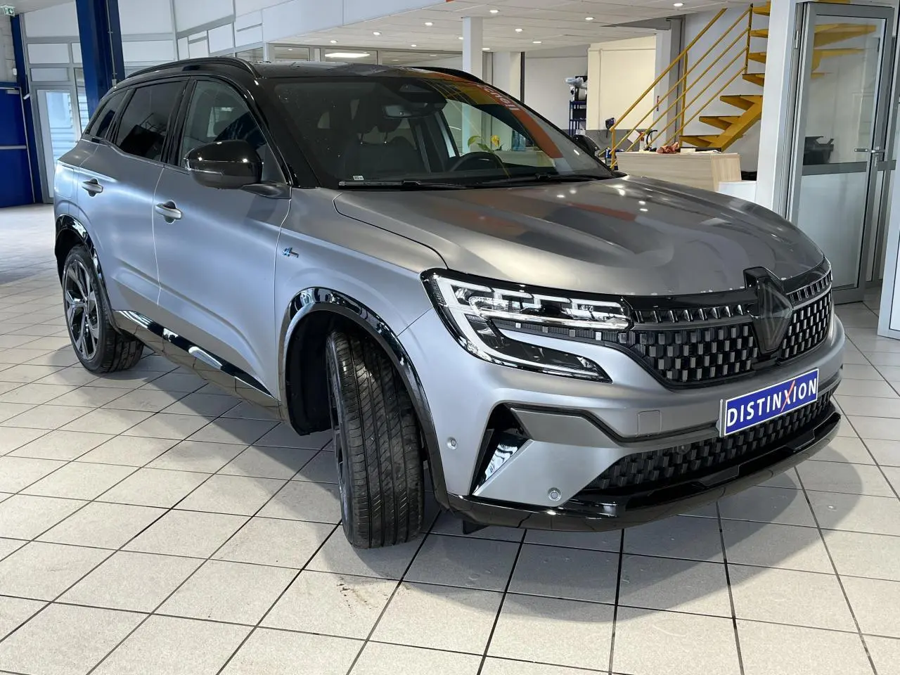 Renault Austral gris schiste en 3/4 avant droit, avec calandre damier ice black et jantes alliage 20 pouces.