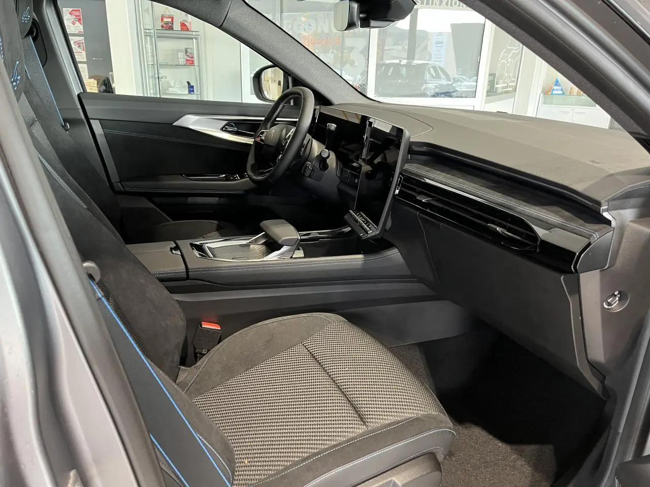 Vue intérieure côté conducteur du Renault Austral 2025 gris, avec sellerie tissu carbone Alcantara et écran tactile vertical.