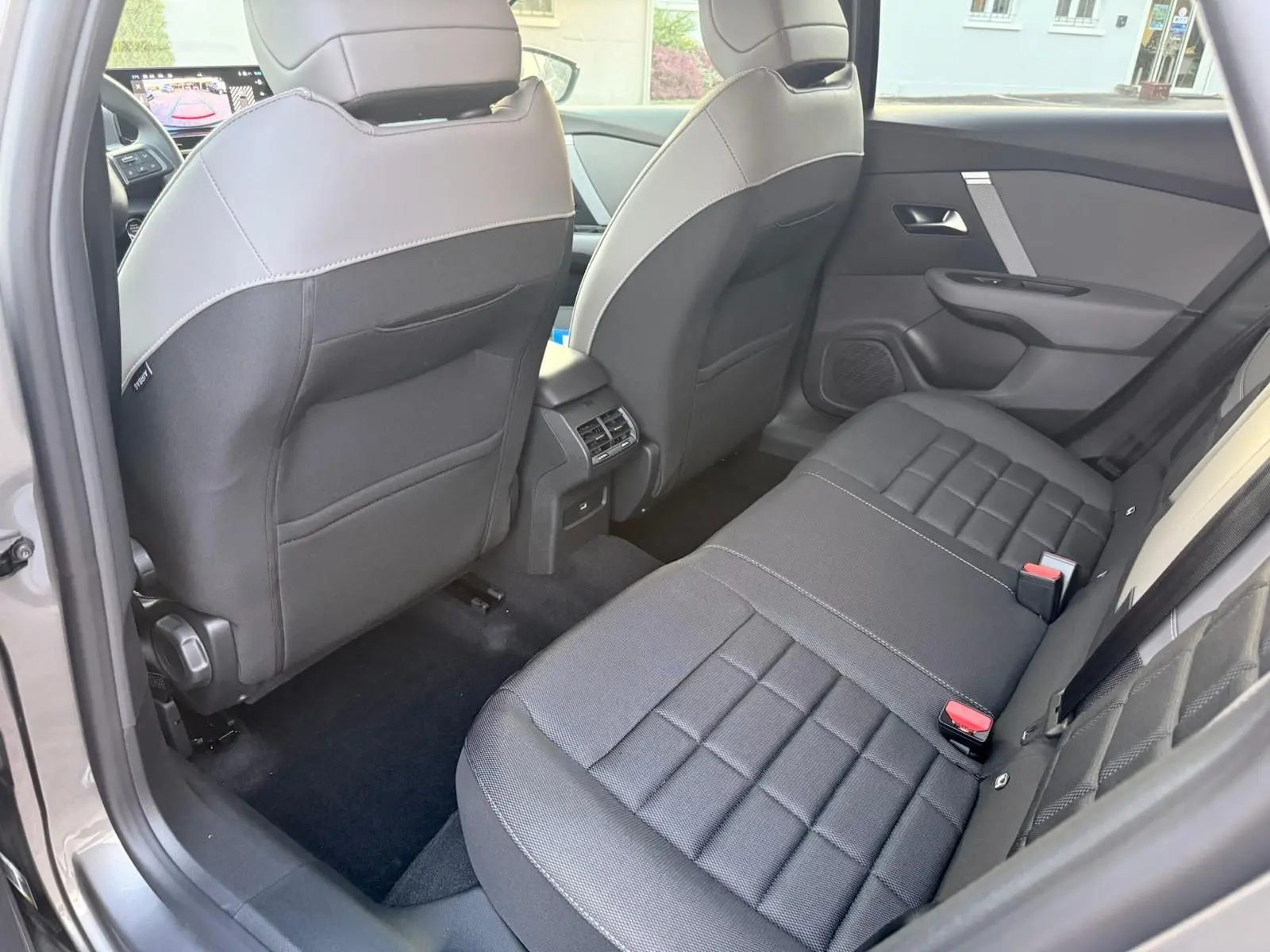 Vue intérieure arrière droite du Citroën C4 hybride gris Mercury, montrant les sièges arrière et les dossiers avant bicolores.