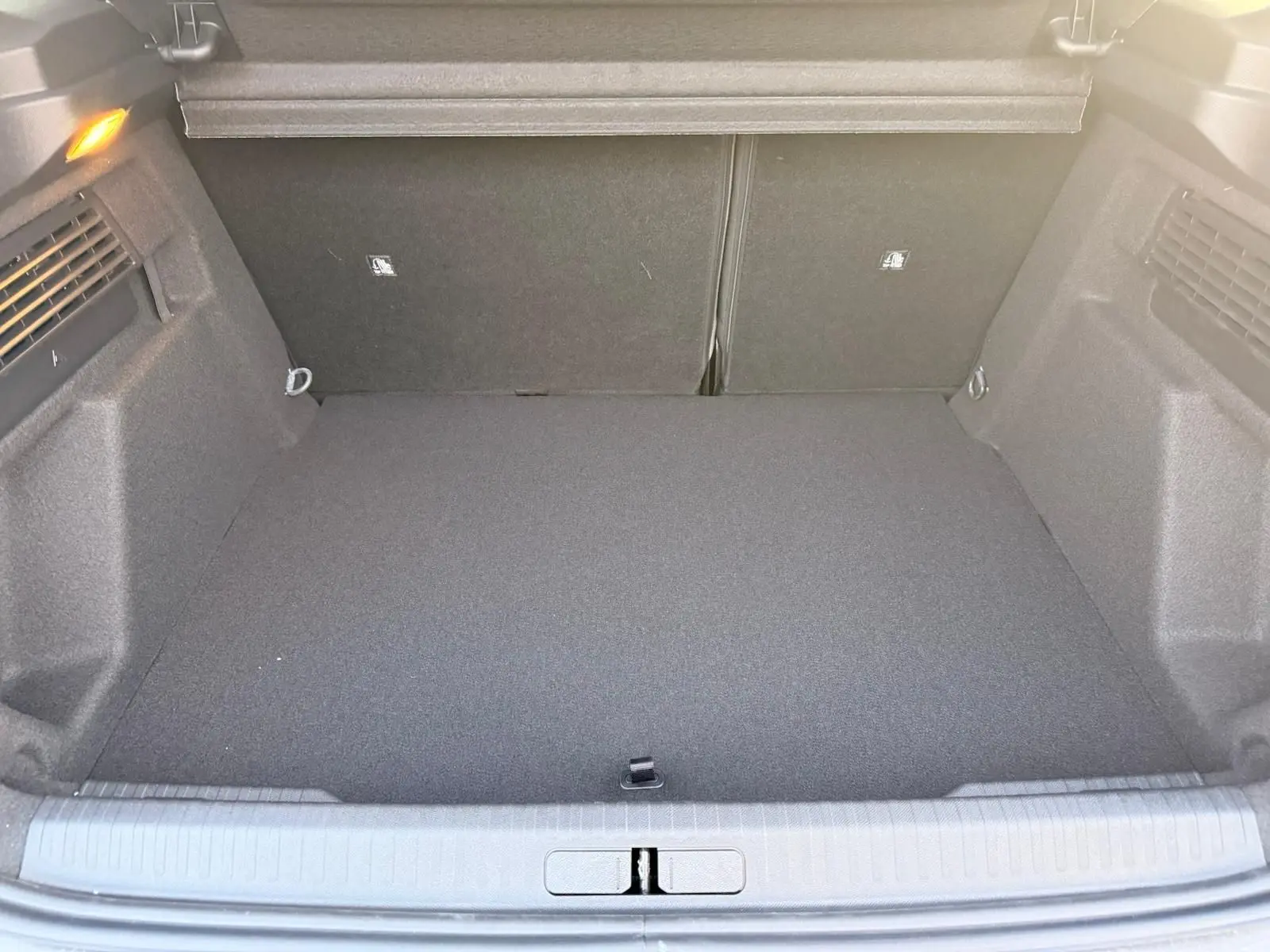 Coffre ouvert du Citroën C4 hybride gris Mercury, vue de l’arrière montrant un espace de chargement propre et spacieux.