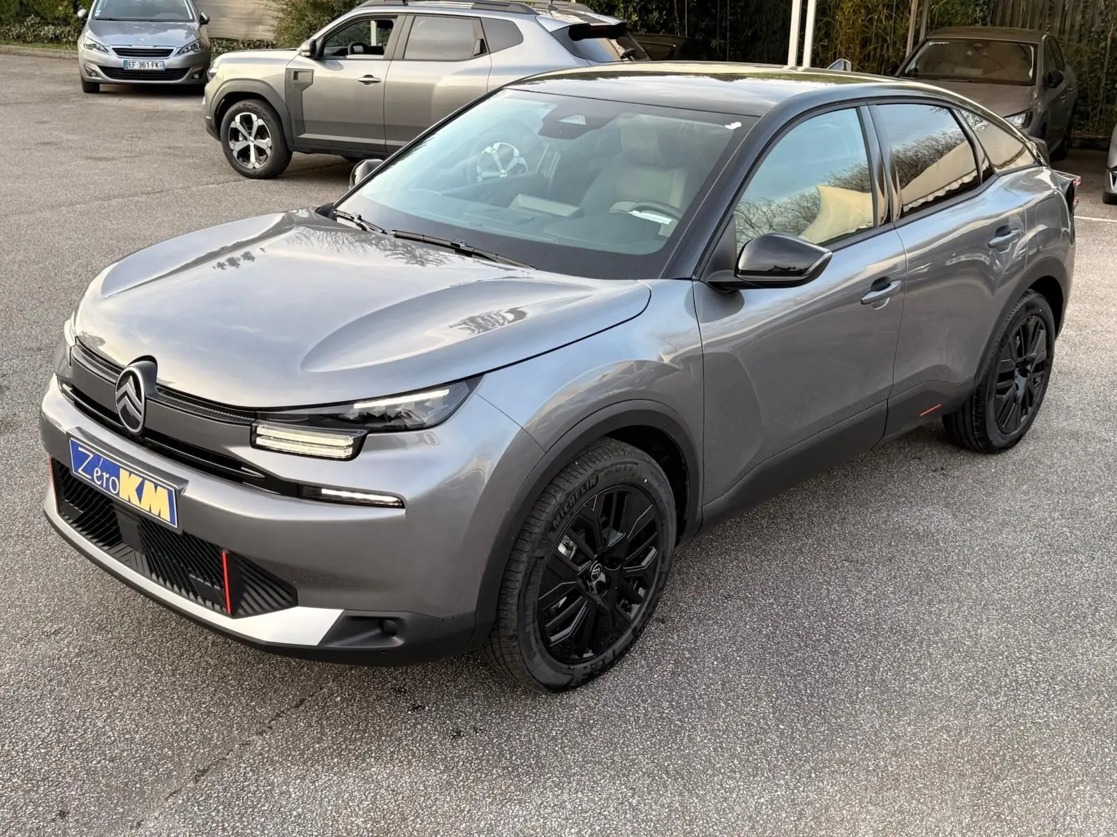 Citroën C4 hybride gris Mercury vue 3/4 avant droit, avec jantes noires et calandre au design épuré.