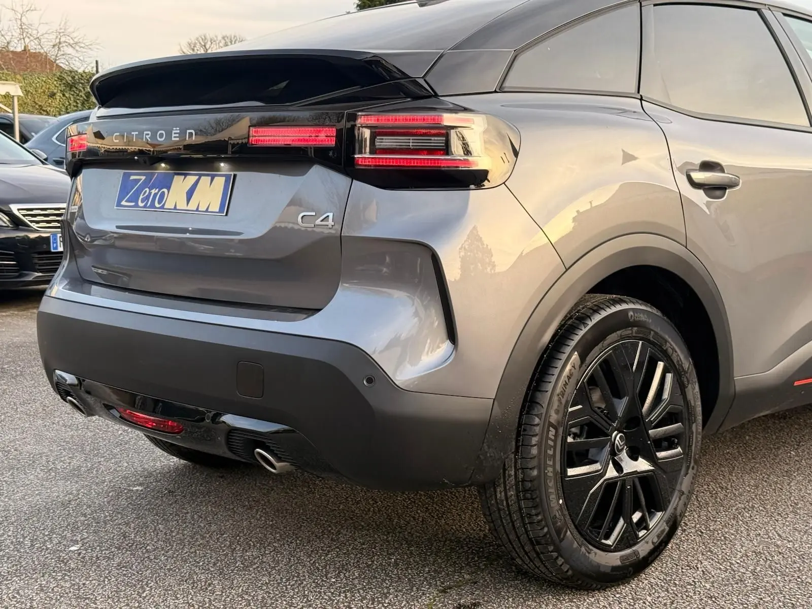 Vue 3/4 arrière droite d'une Citroën C4 gris Mercury 2025 avec feux LED et jantes noires distinctives.