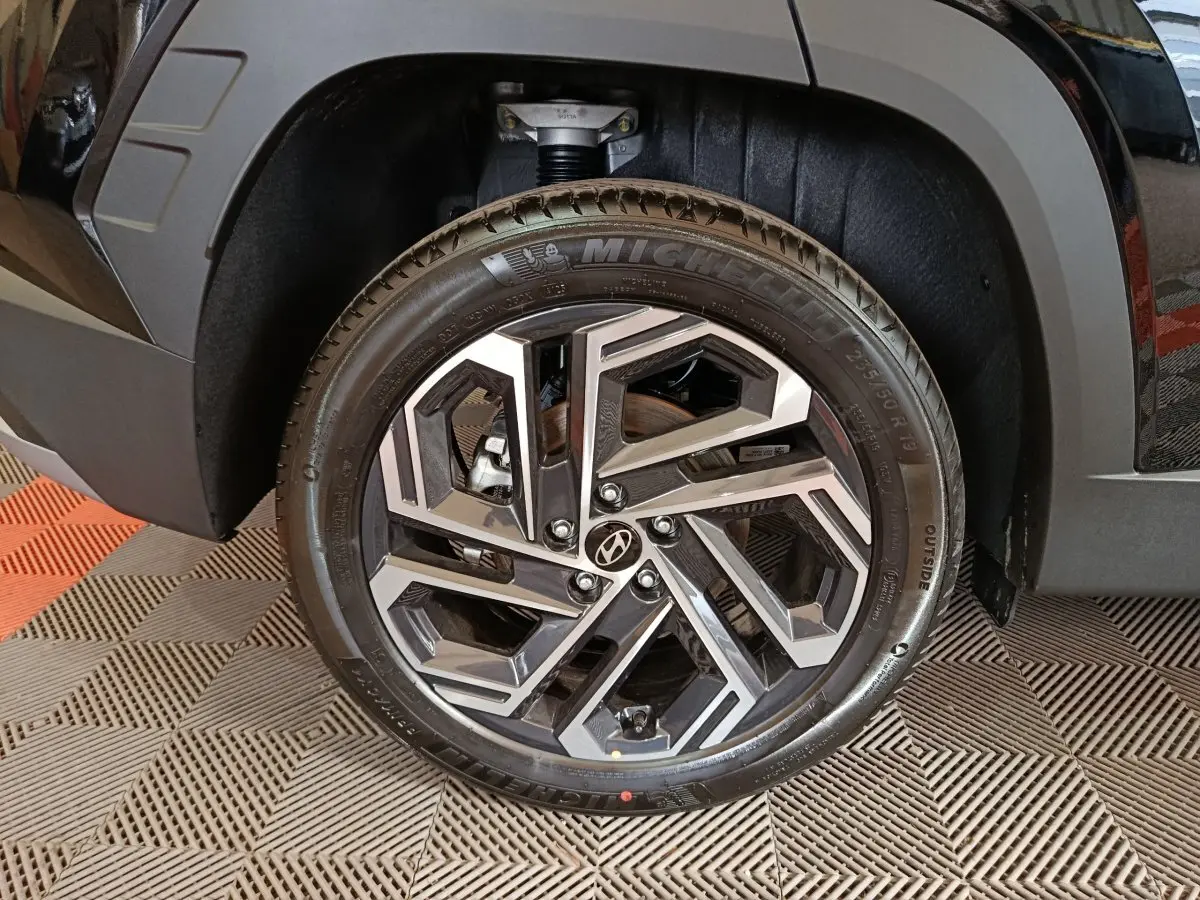 Gros plan sur la roue avant droite du Hyundai Tucson noir 2025 avec jante alliage au design géométrique.